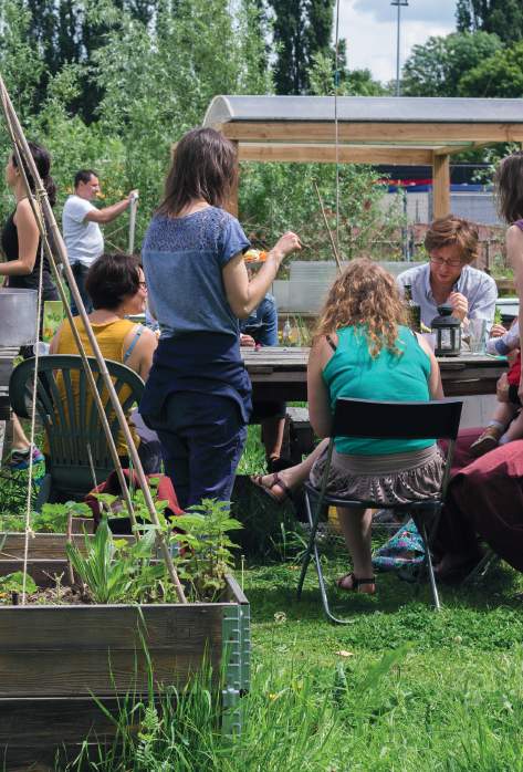 People gather at an outdoor table in the Josaphat community garden in Brussels.