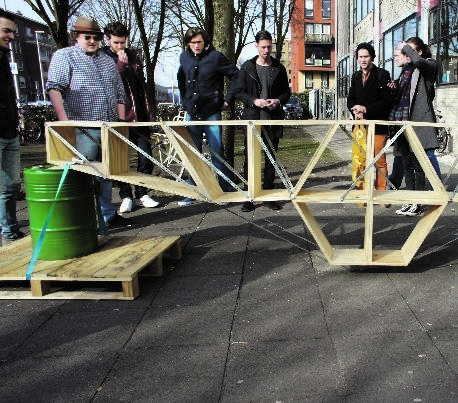 Students stand beside a timber truss bridge assembled during a construction design exercise.