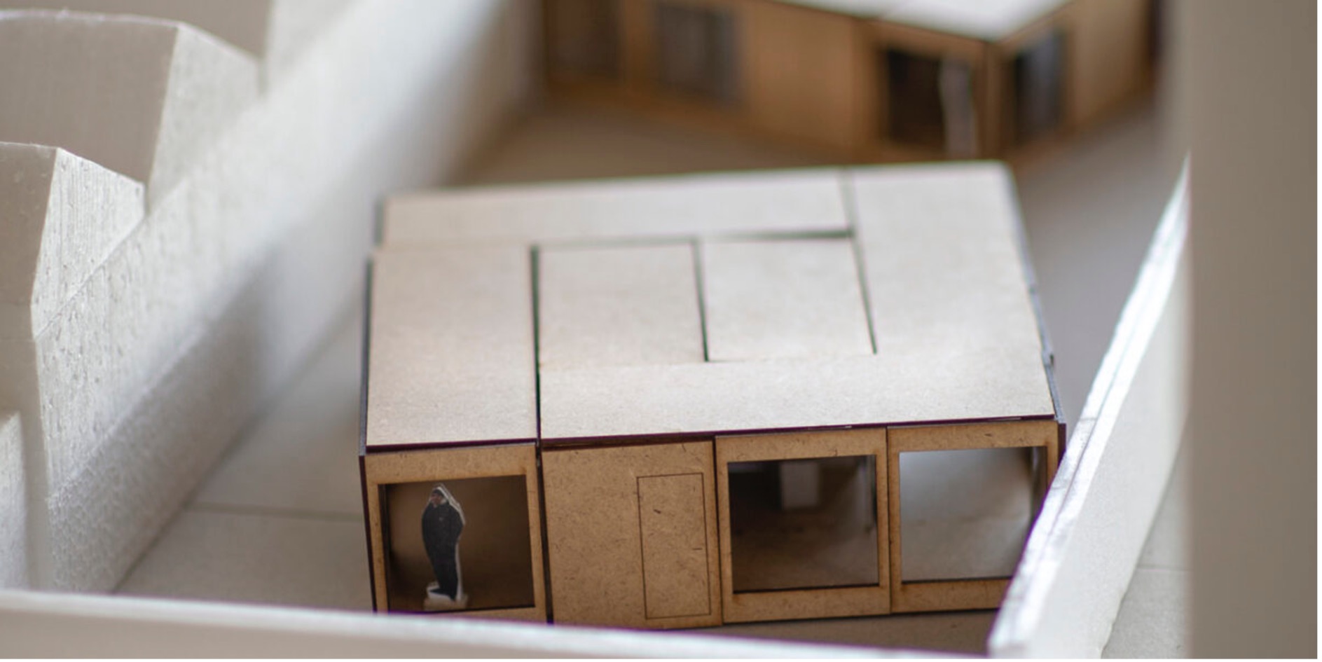 Architectural model showing modular timber homes arranged within their urban surroundings
